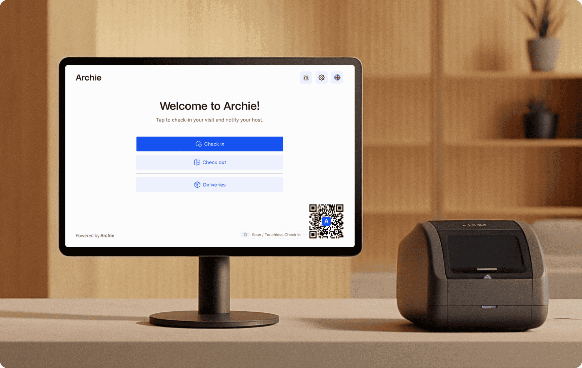 Reception desk setup with a monitor showing the Archie visitor welcome/check-in screen next to a desktop badge printer.