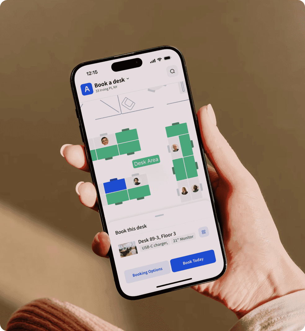 Hand holding a phone showing a desk booking map interface.