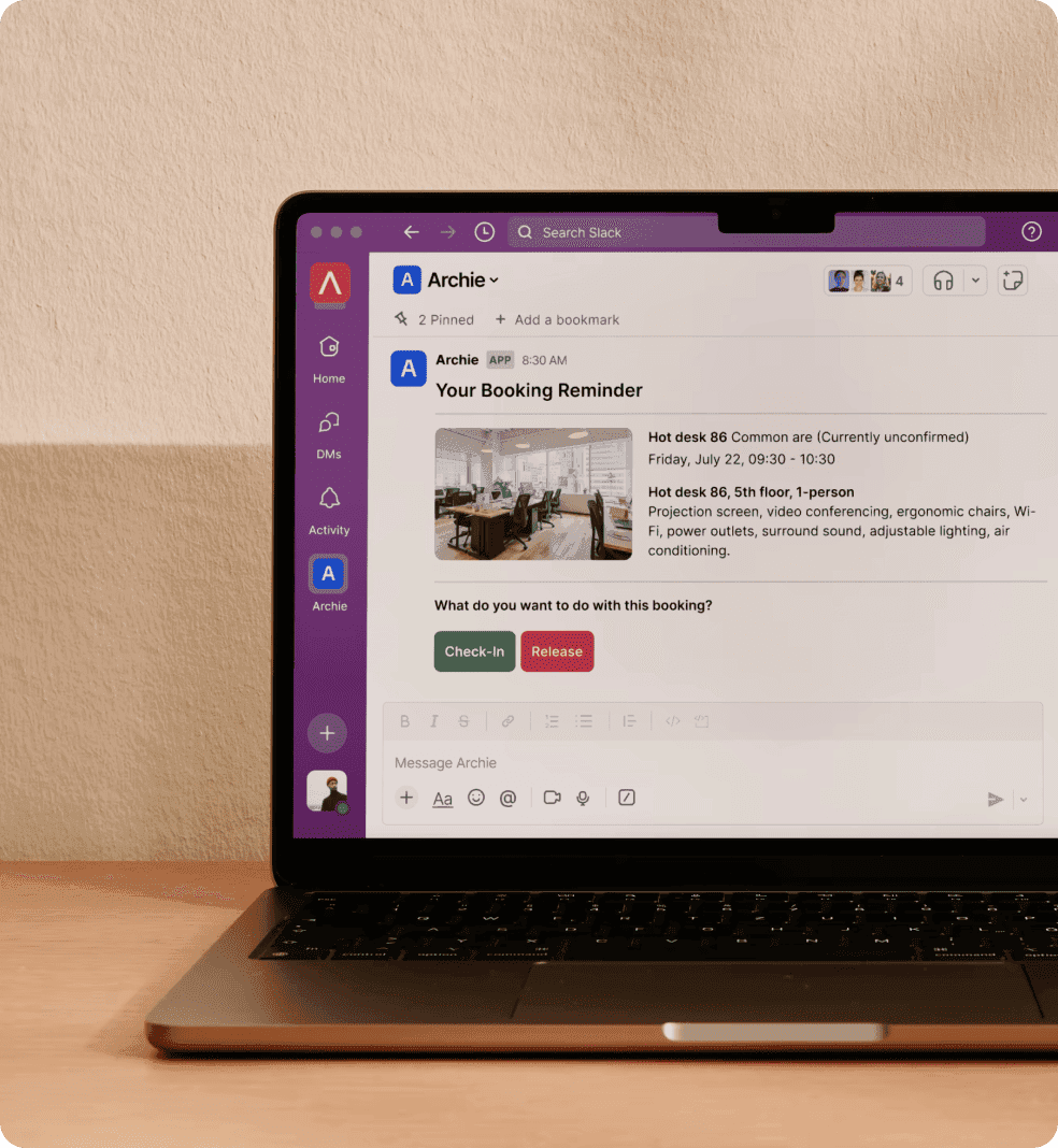 Laptop screen displaying Slack booking reminder for a hot desk workspace.