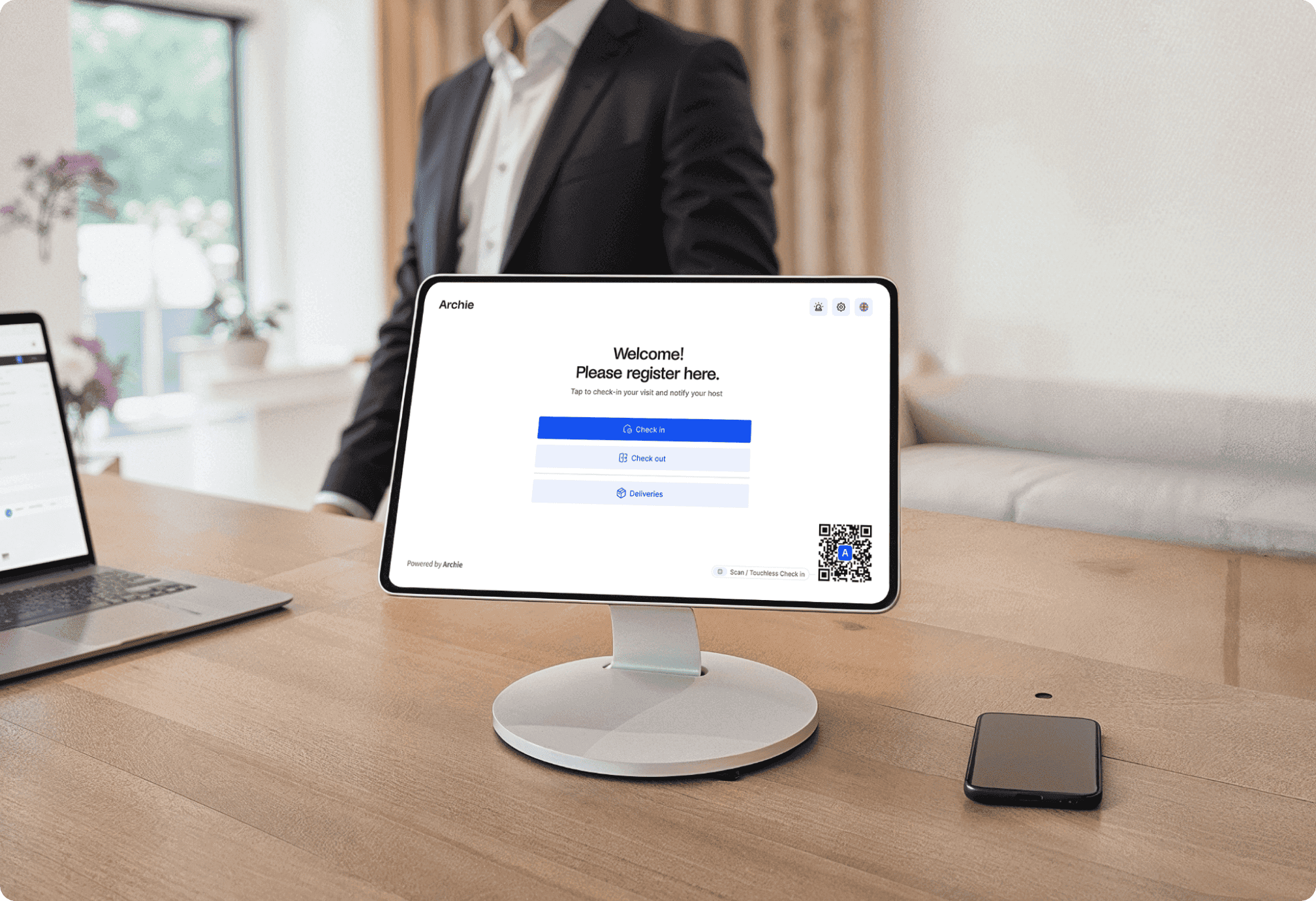 Digital visitor registration screen displayed on a tabletop monitor, with person standing nearby