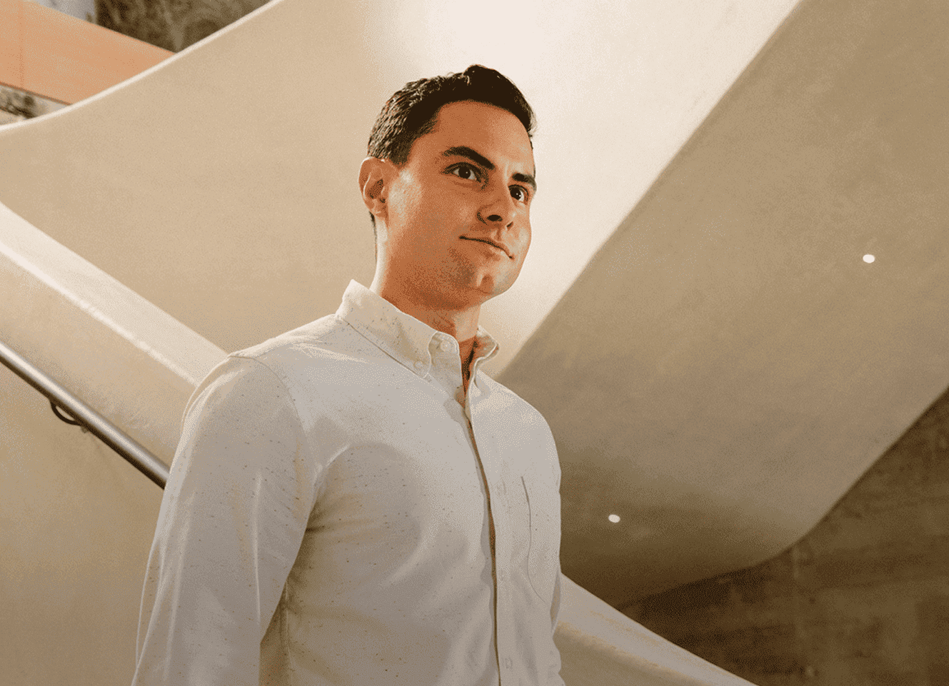 Un homme en chemise blanche debout près d'un escalier
