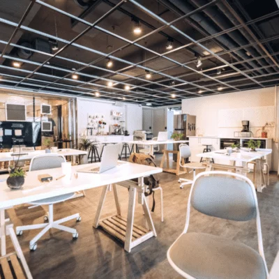 A modern coworking space with white desks, ergonomic chairs, and laptops.