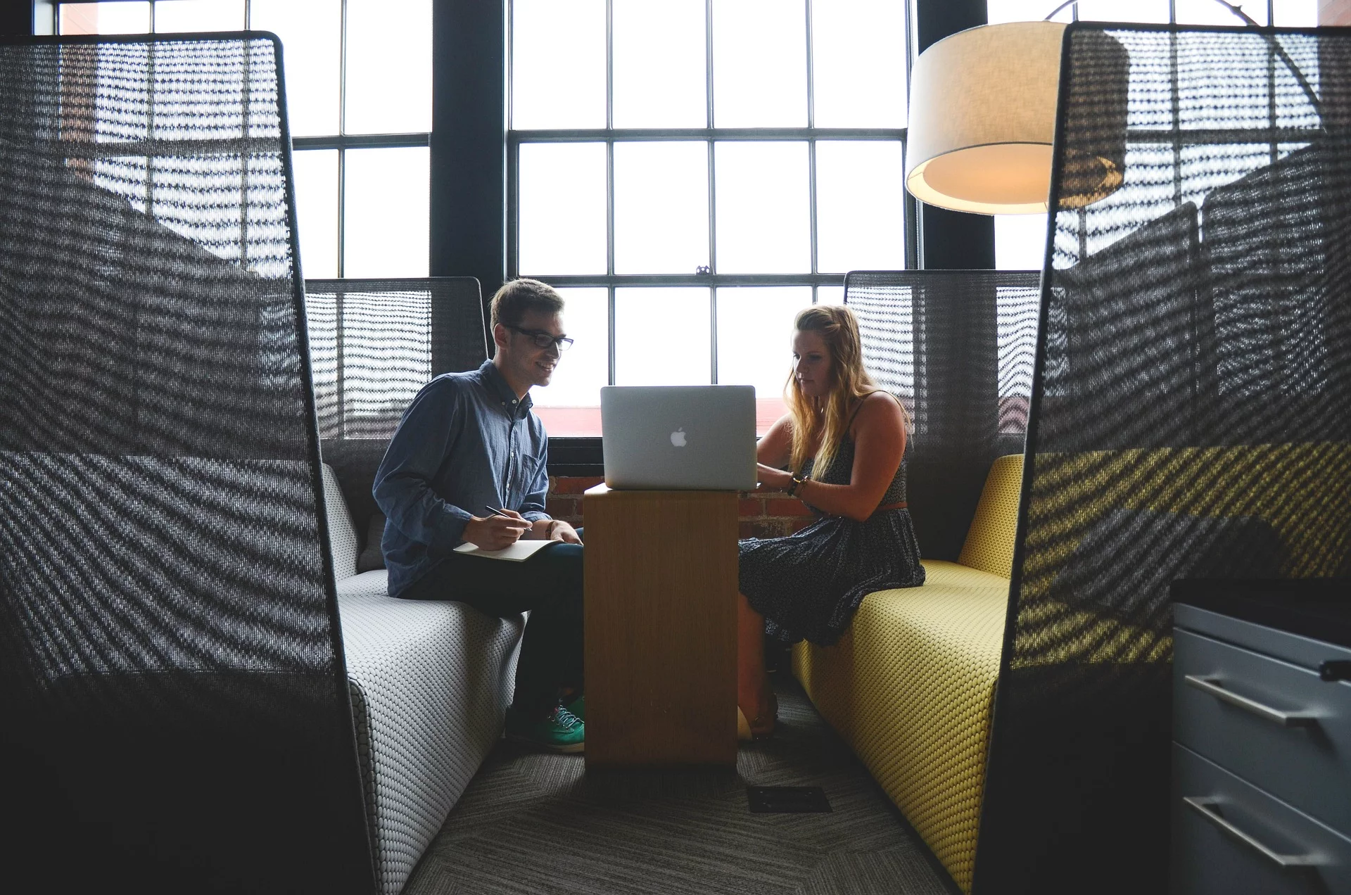 Two people collaborating in a modern office lounge area with a casual and inviting atmosphere.