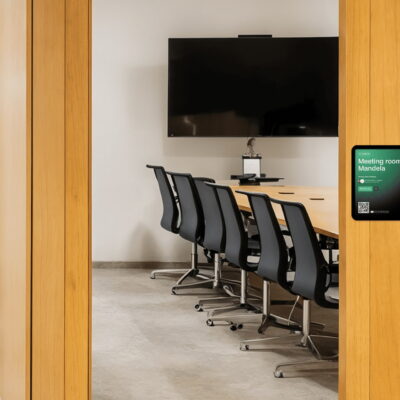 Modern meeting room with a wall-mounted room booking display showing availability for “Meeting room Mandela.”