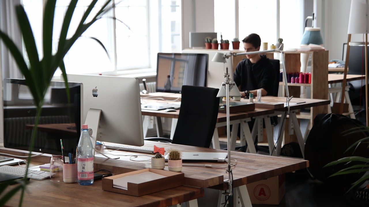 A modern office space with people working behind hot desks.