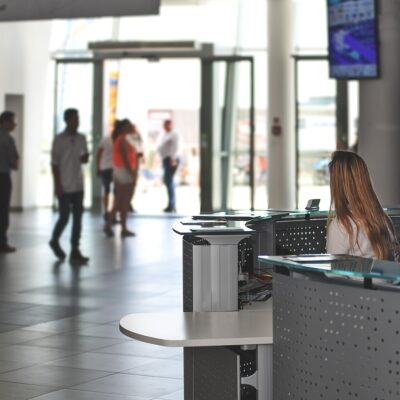 A reception area with a front desk on the right, where a woman is seated.