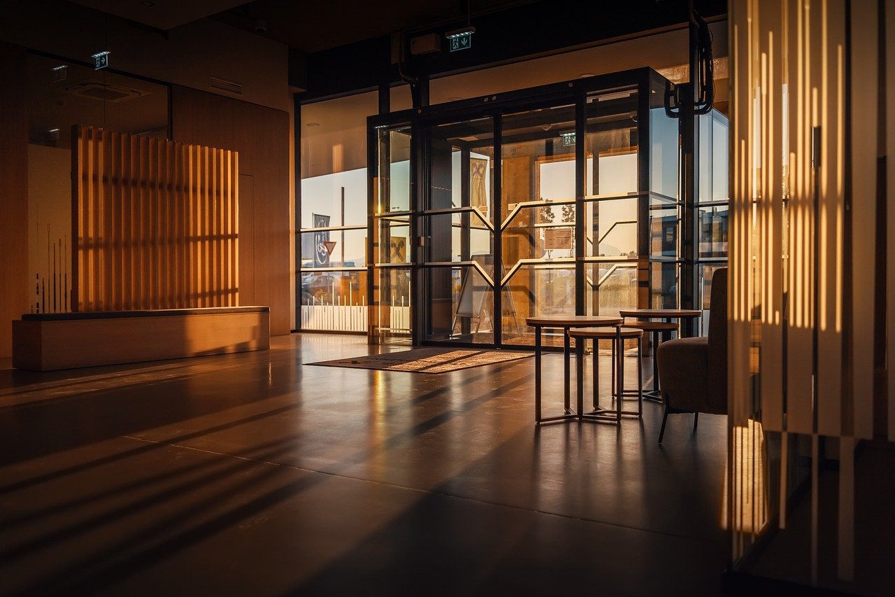 A modern lobby area with warm lighting from the evening sun streaming through glass doors.