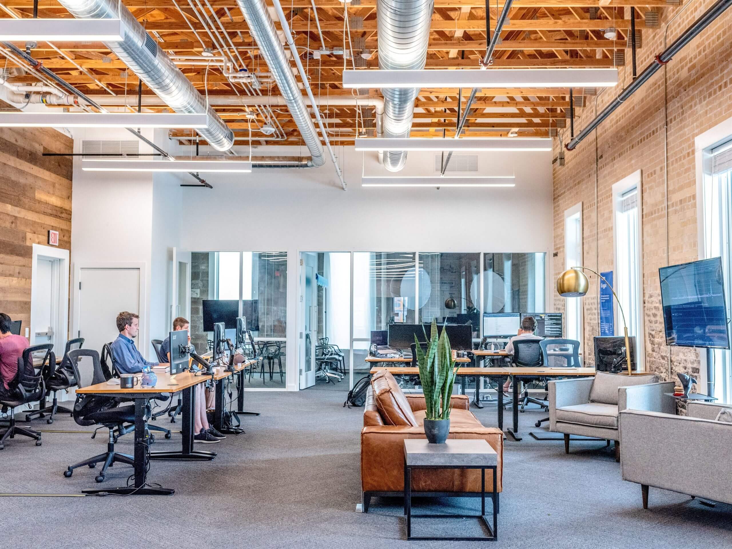 An open-plan office with workstations and employees working at desks equipped with computers.