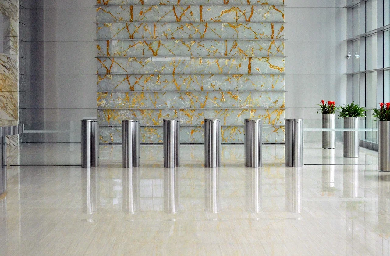 A modern building lobby with a sleek security entrance featuring metal turnstiles.