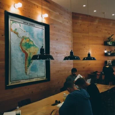 A cozy coworking space with wooden walls, warm lighting, and a large map of South America.