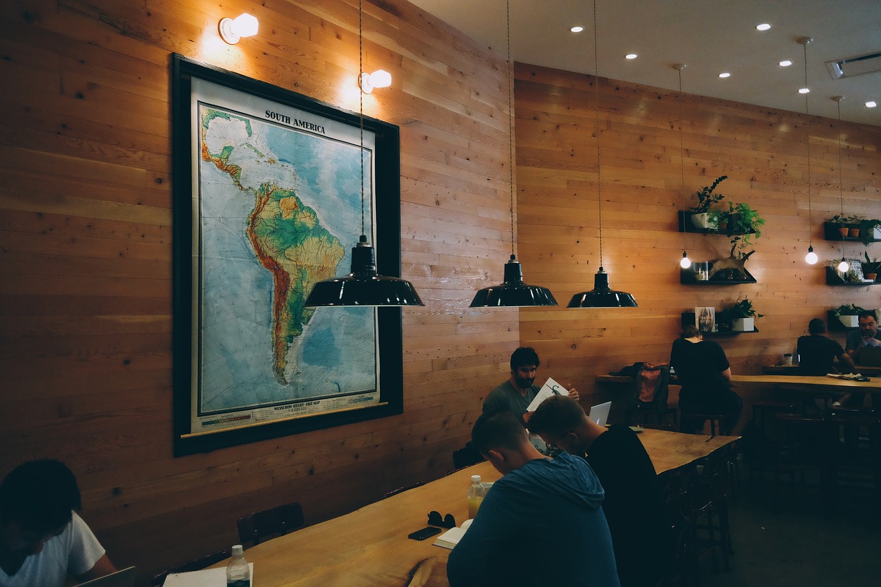 A cozy coworking space with wooden walls, warm lighting, and a large map of South America.