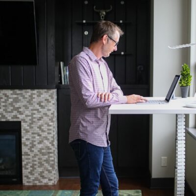 A man working at a laptop in a modern, open office space with other people in the background.