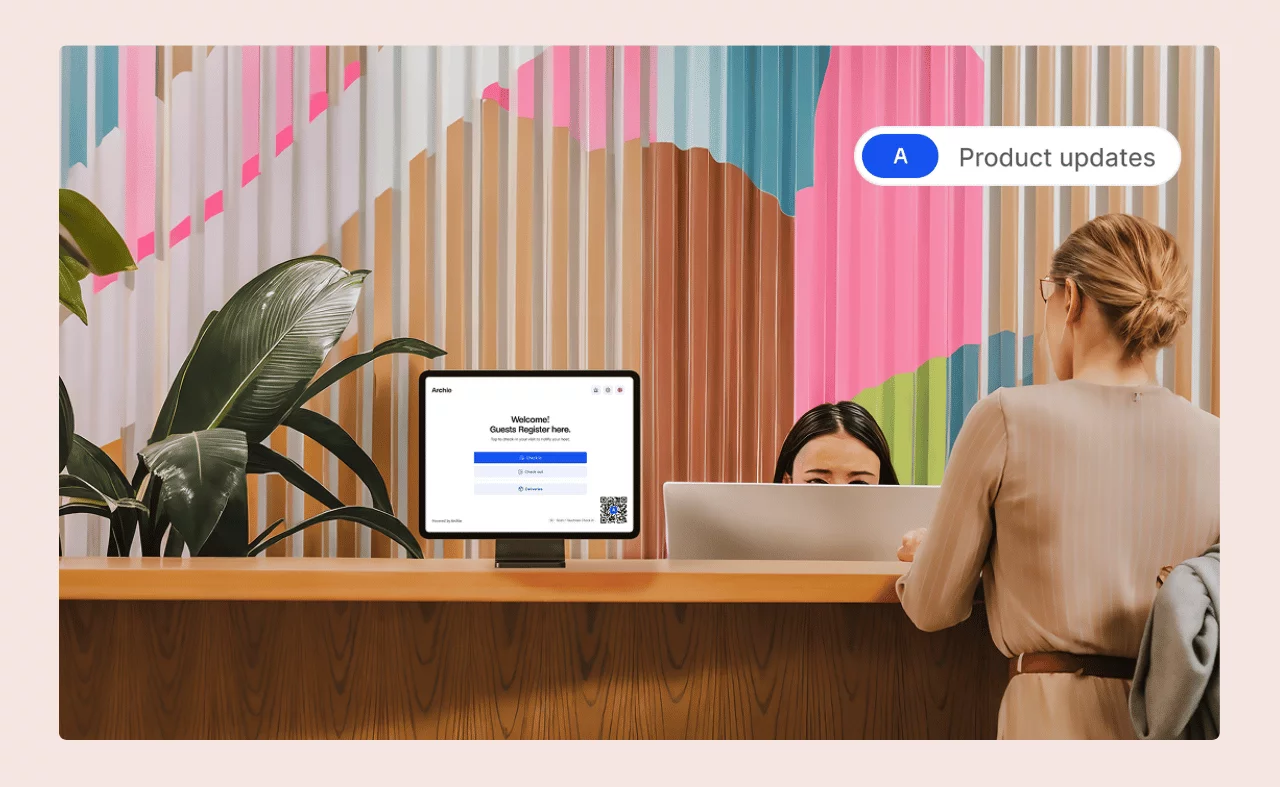 A woman checks in at a modern office reception desk with a visitor registration screen, while a receptionist sits behind a computer.