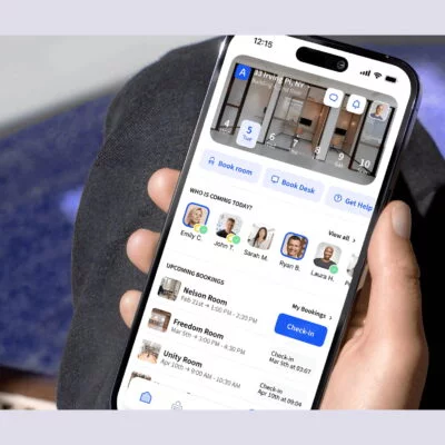 Hand holding a smartphone showing the Archie app interface with desk and room booking options.