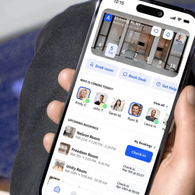 Hand holding a smartphone showing the Archie app interface with desk and room booking options.