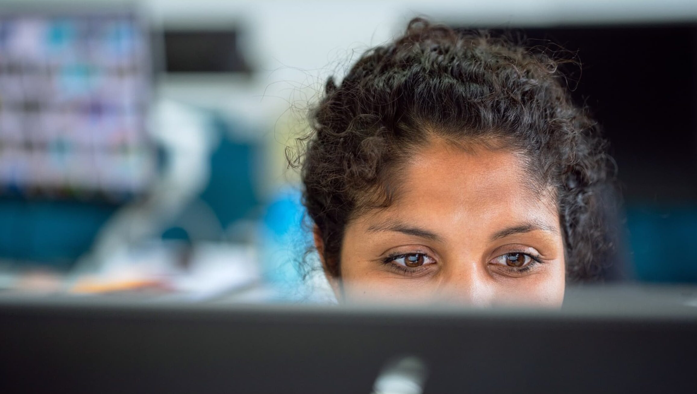 Close-up of a woman focused on her computer screen in an office setting.