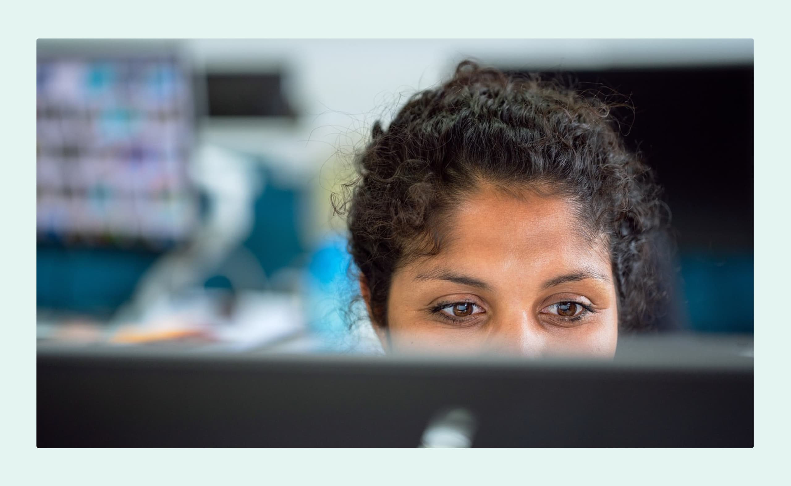 Close-up of a woman focused on her computer screen in an office setting.