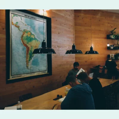 A cozy coworking space with wooden walls, warm lighting, and a large map of South America.