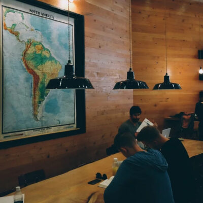 A cozy coworking space with wooden walls, warm lighting, and a large map of South America.