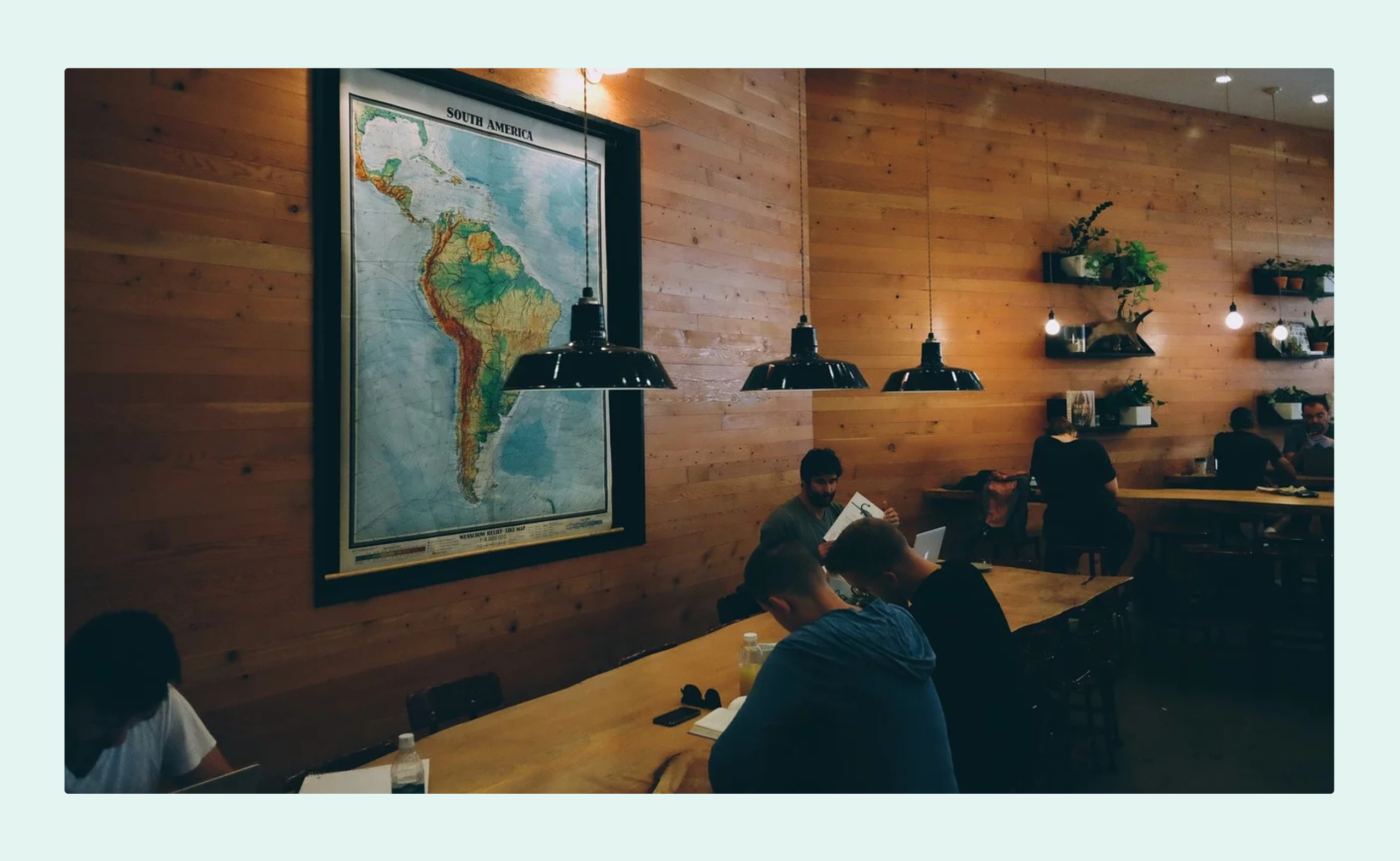 A cozy coworking space with wooden walls, warm lighting, and a large map of South America.