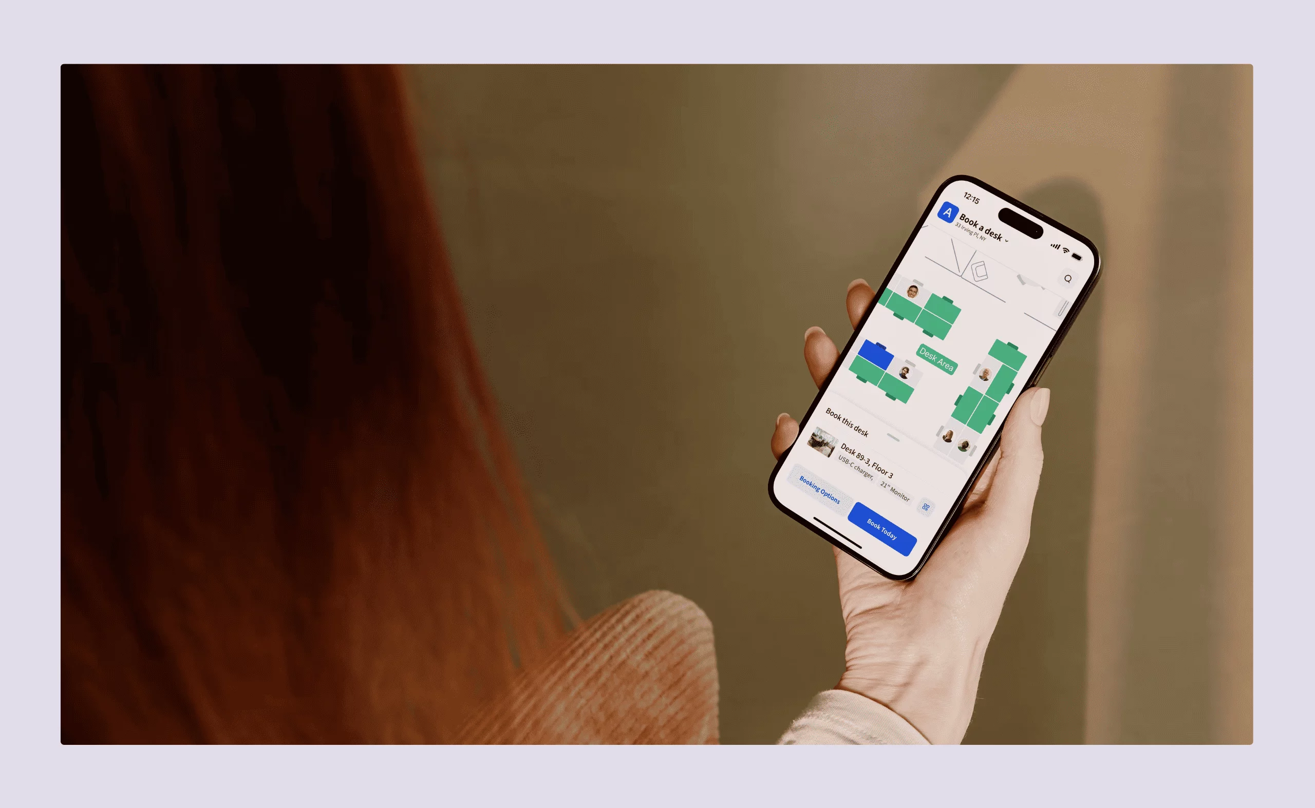 Person holding a smartphone with Archie’s desk booking app open, showing a digital office floor plan and available desks.