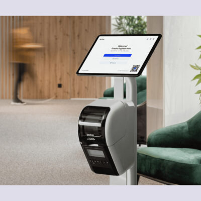 Archie's digital check-in kiosk with a touchscreen and badge printer set up in a modern office lobby, displaying a guest registration form.