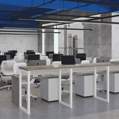 Modern open-plan office with rows of desks, white chairs, and desktop computers under a blue ceiling.