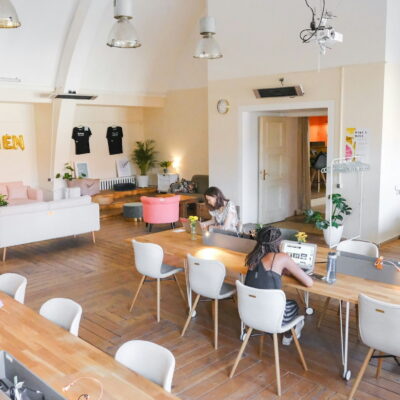 Bright coworking space with women working at shared wooden desks and cozy sofas.
