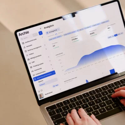 Close-up of a person using a laptop with the Archie coworking software dashboard open, showing analytics and space usage charts.