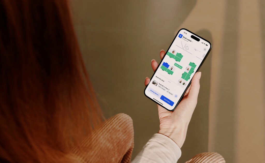 Une personne tenant un smartphone sur lequel est ouverte réservation de bureaux Archie, avec un plan des étages.