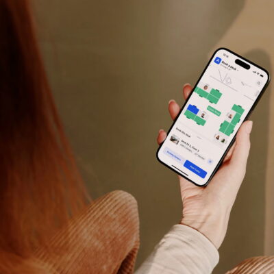 Person holding a smartphone using Archie desk booking app with an office floor plan.