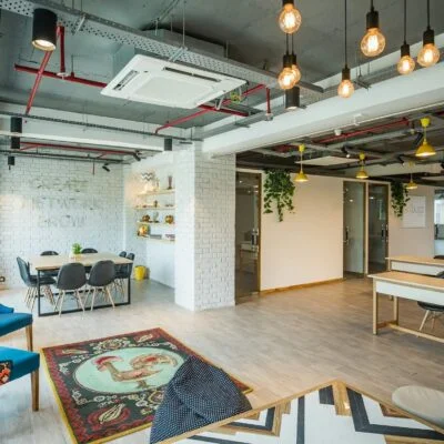 Modern coworking space with open desks, meeting areas, and lounge seating in a bright shared office.