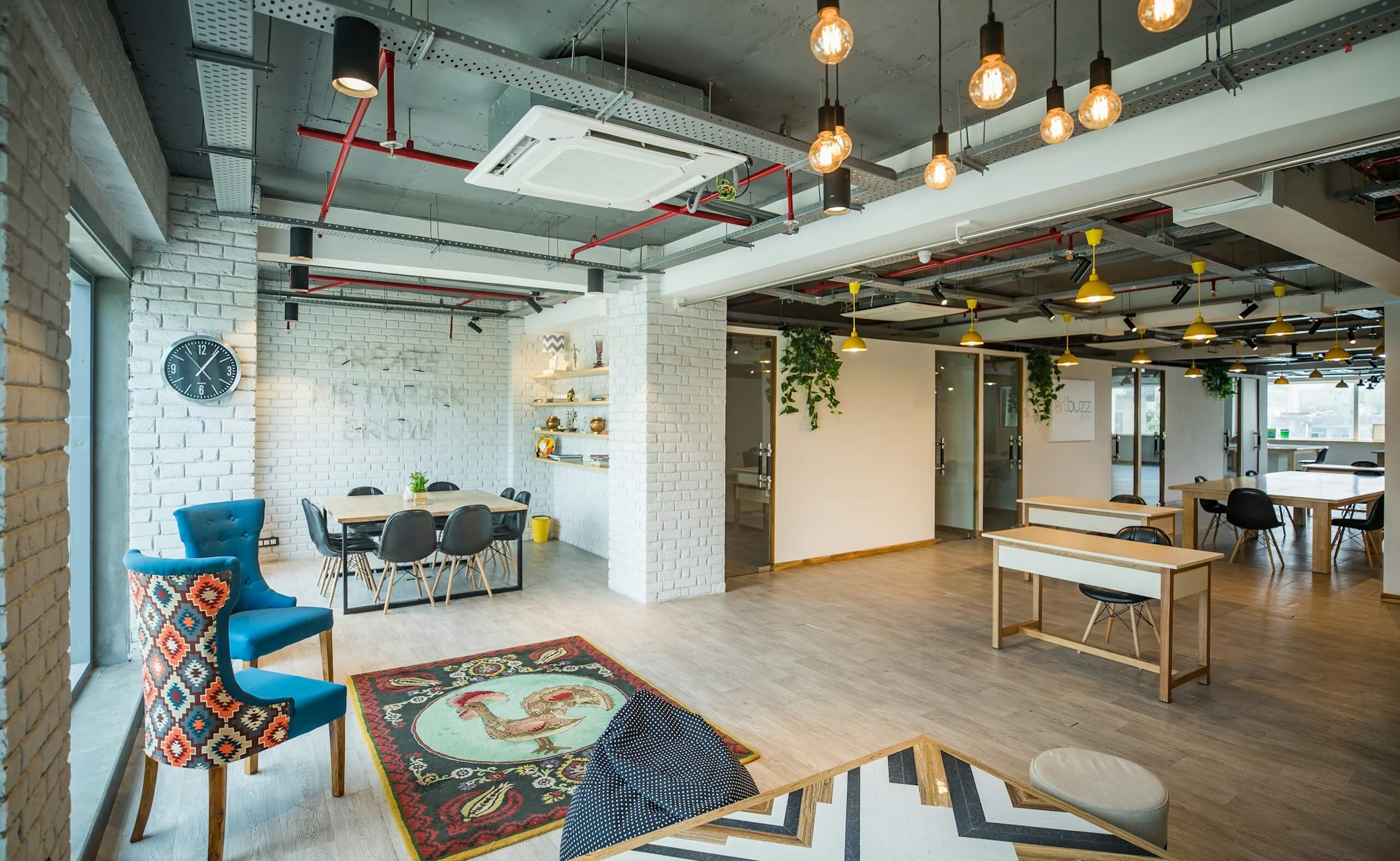 Modern coworking space with open desks, meeting areas, and lounge seating in a bright shared office.
