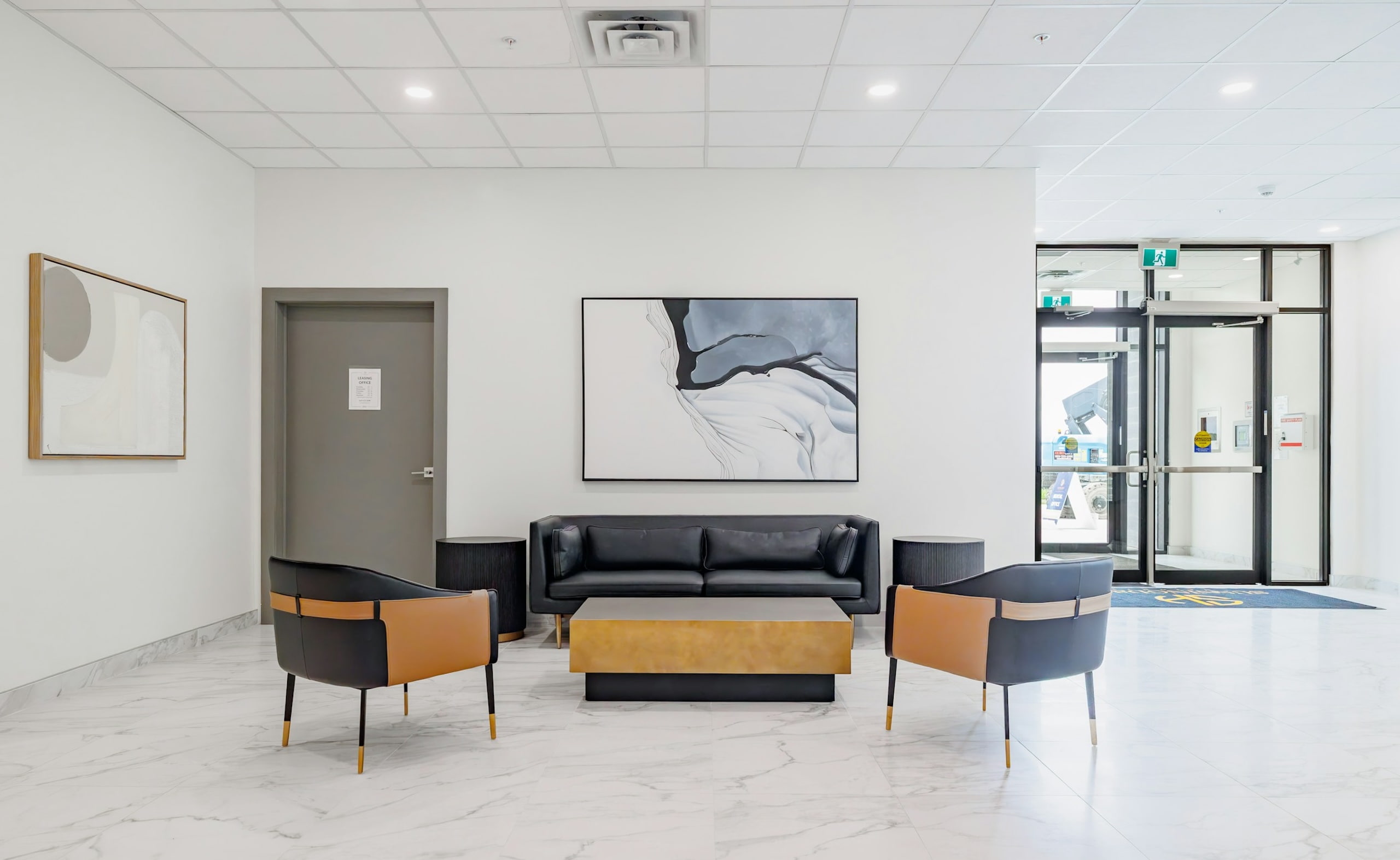 Modern office lobby with sofa seating area and glass entrance doors.