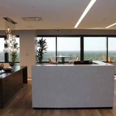 Modern office reception area with front desk, seating, and large windows overlooking the city.