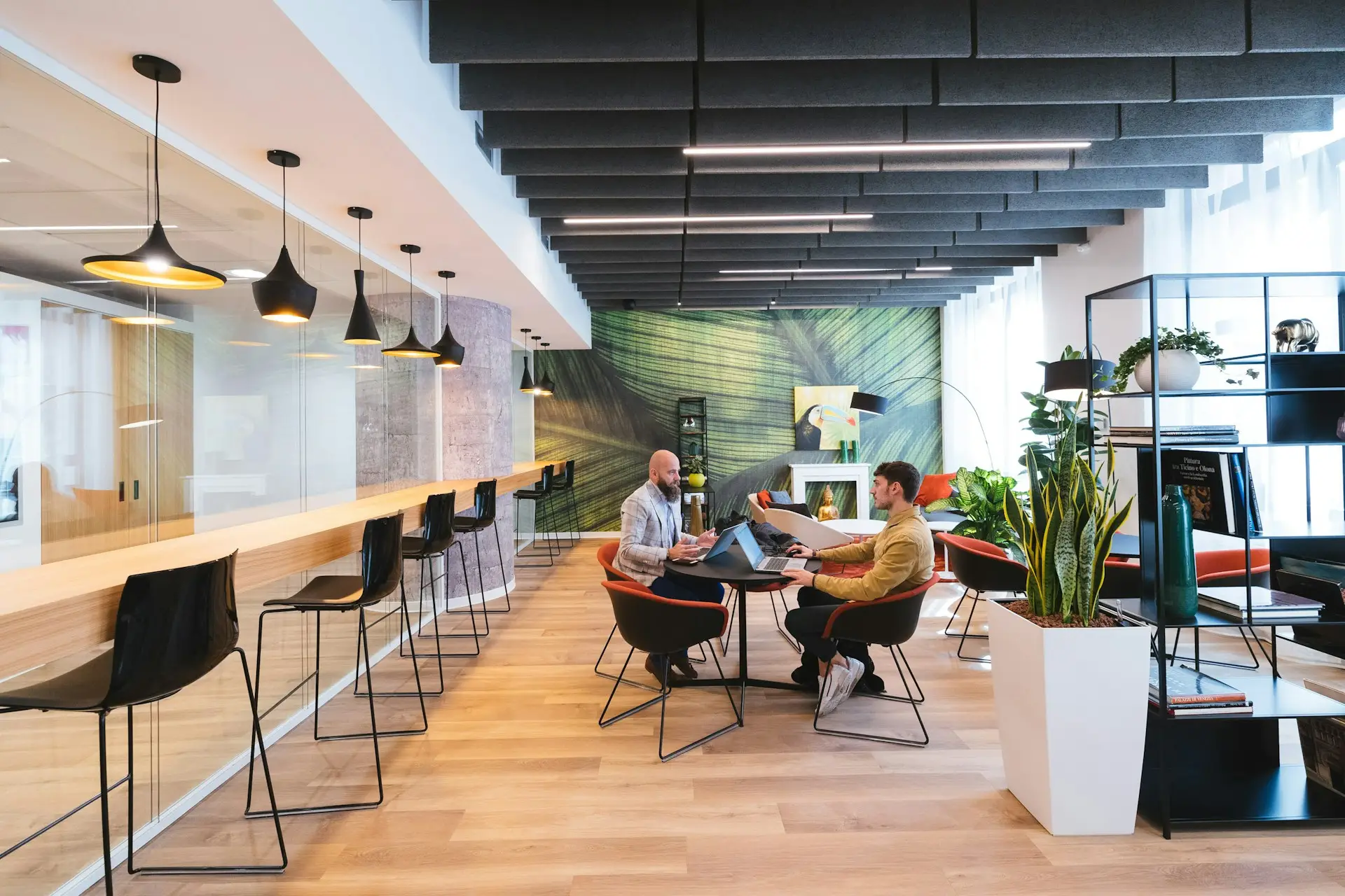 People collaborating in a modern coworking space with lounge seating, bar workstations, and shared work areas.